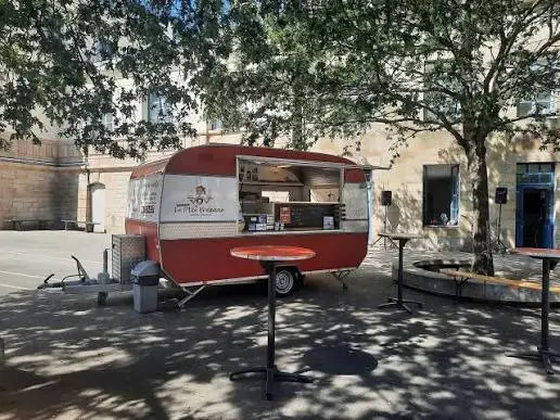 La caravane crêpes à l'ombre d'un arbre, mange-debout rouges installés devant