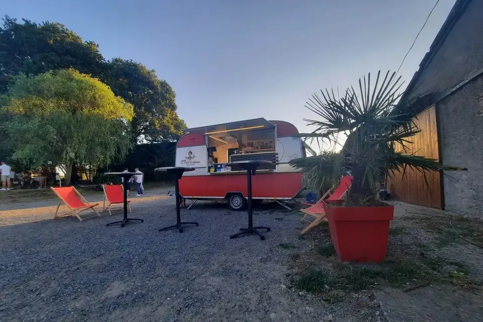 La caravane rétro en fin de journée, transats rouges et mange-debout devant