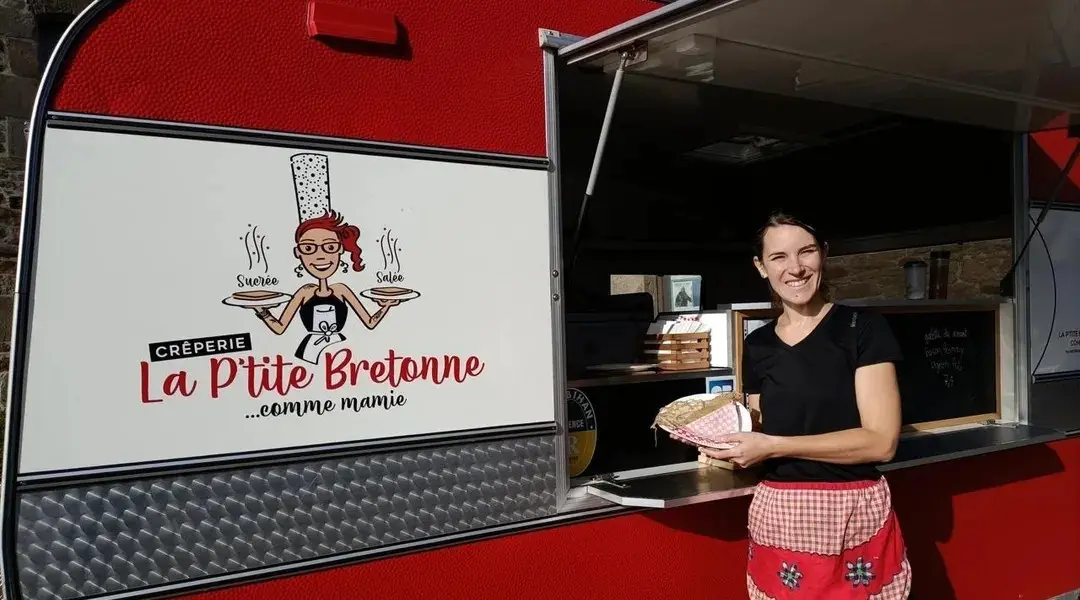 Perrine Marseille devant sa caravane La P'tite Bretonne comme mamie, une galette à la main