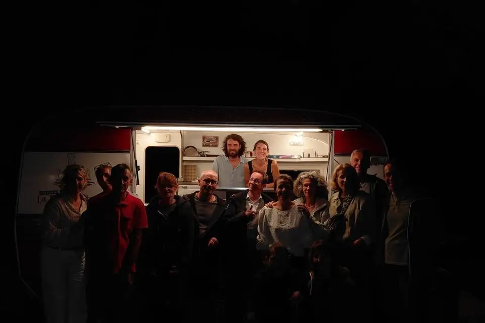 Groupe réuni de nuit devant la caravane éclairée